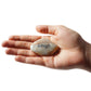 Hand holding a stone with 'Laugh' engraved on it against a white background