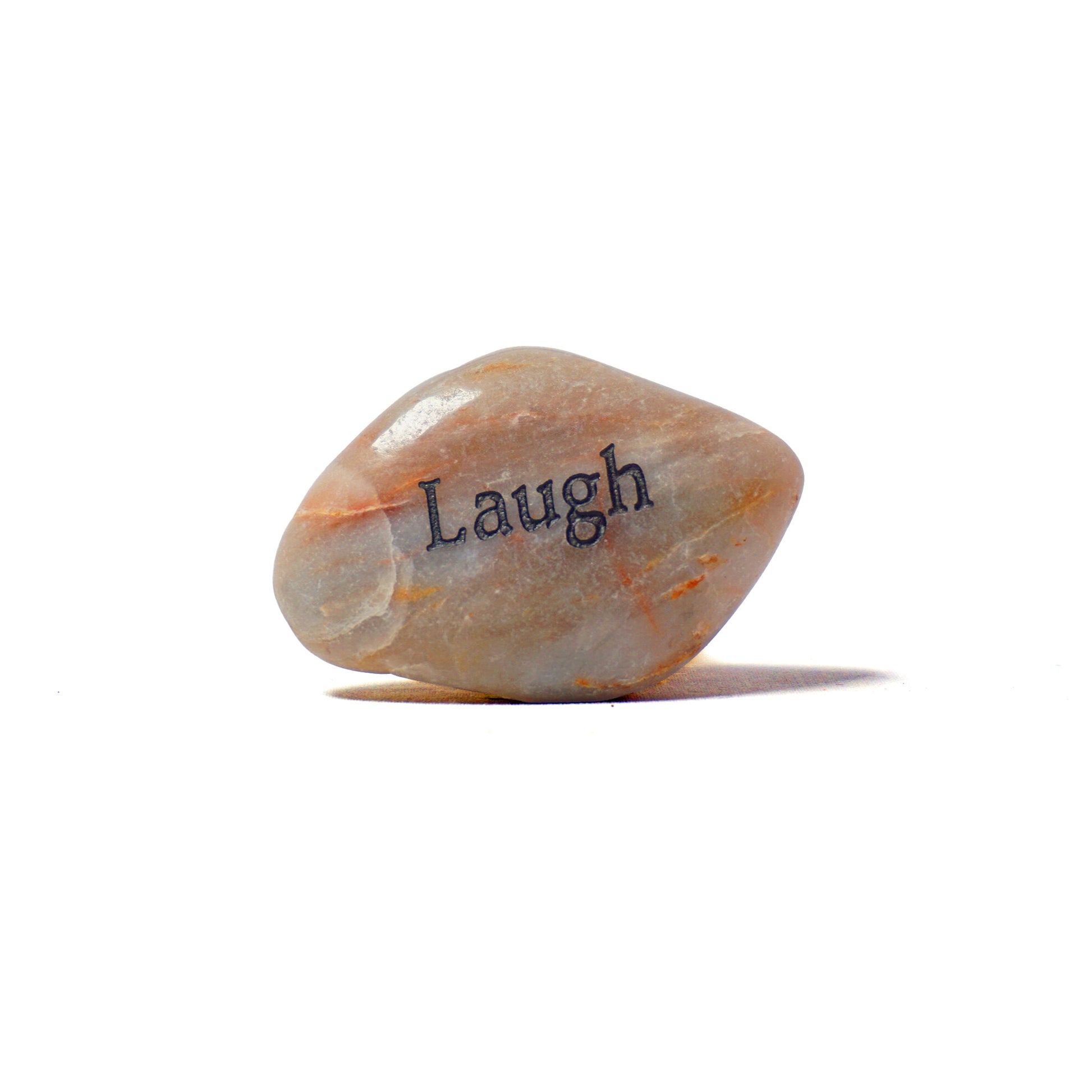 Decorative stone with 'Laugh' engraved on a white background