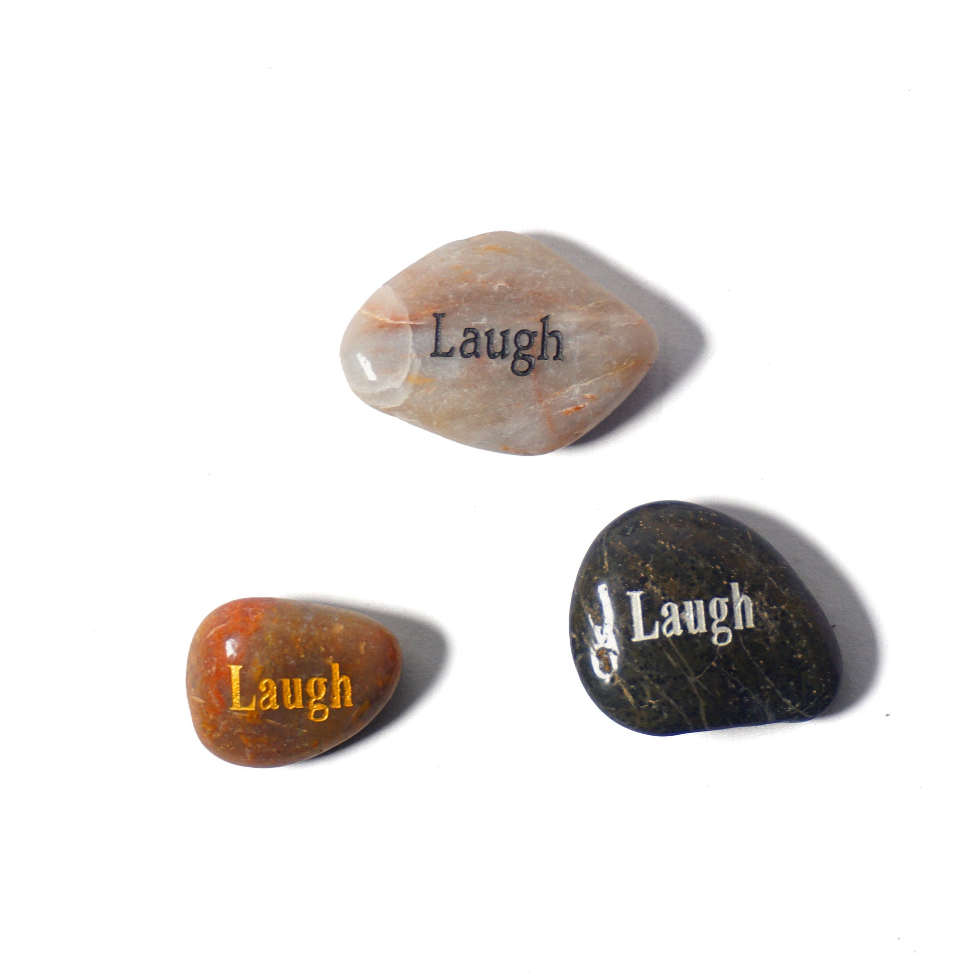 Three stones with 'Laugh' engraved on them on a white background