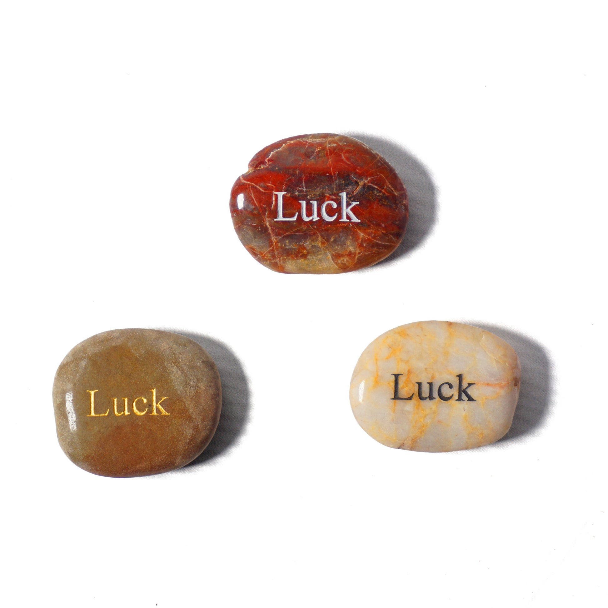 Three stones with 'Luck' engraved on them on a white background