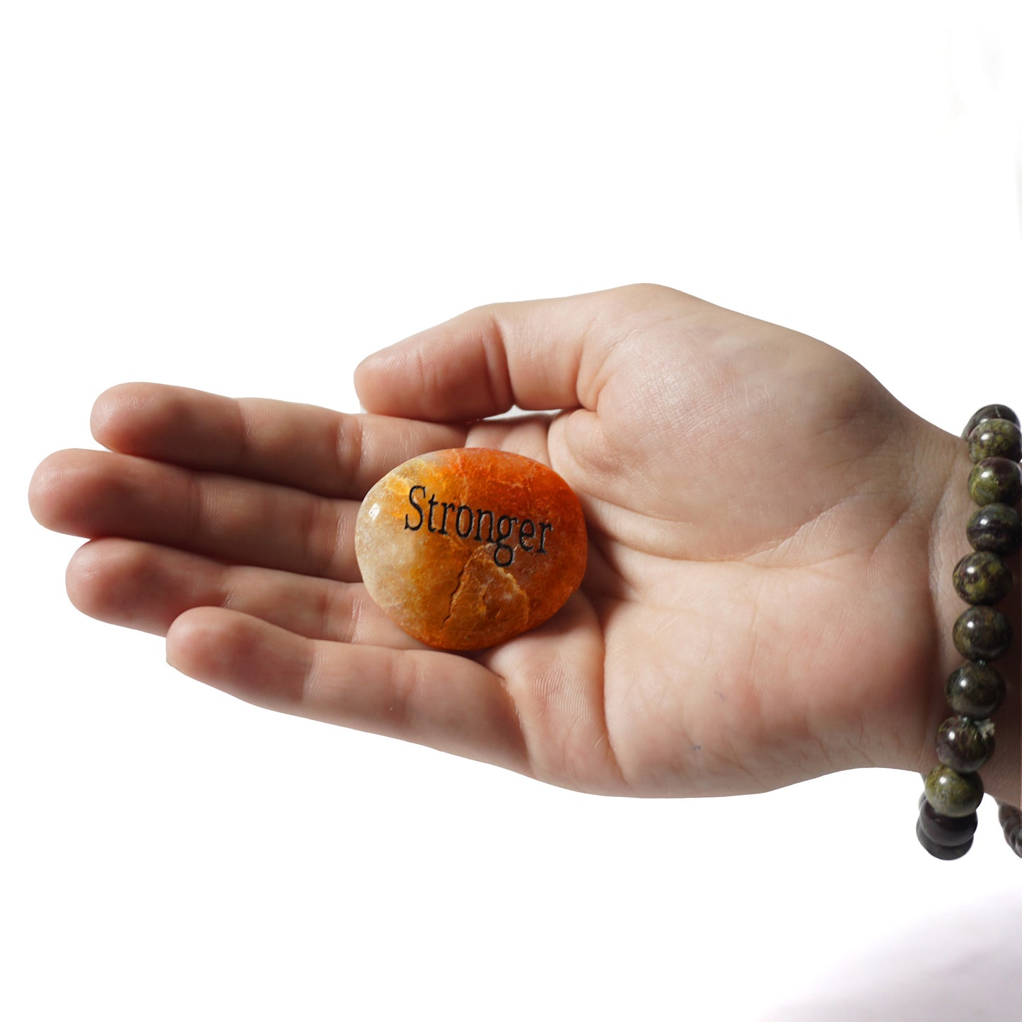 Hand holding a small stone with 'Stronger' engraved on it against a white background
