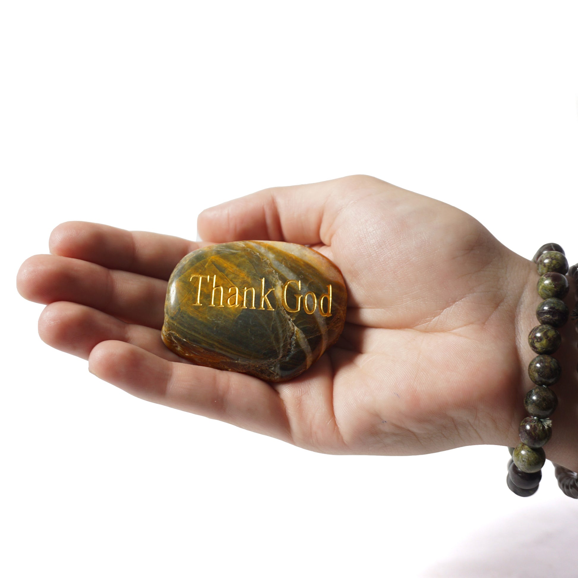 Hand holding a stone with 'Thank God' engraving on a white background