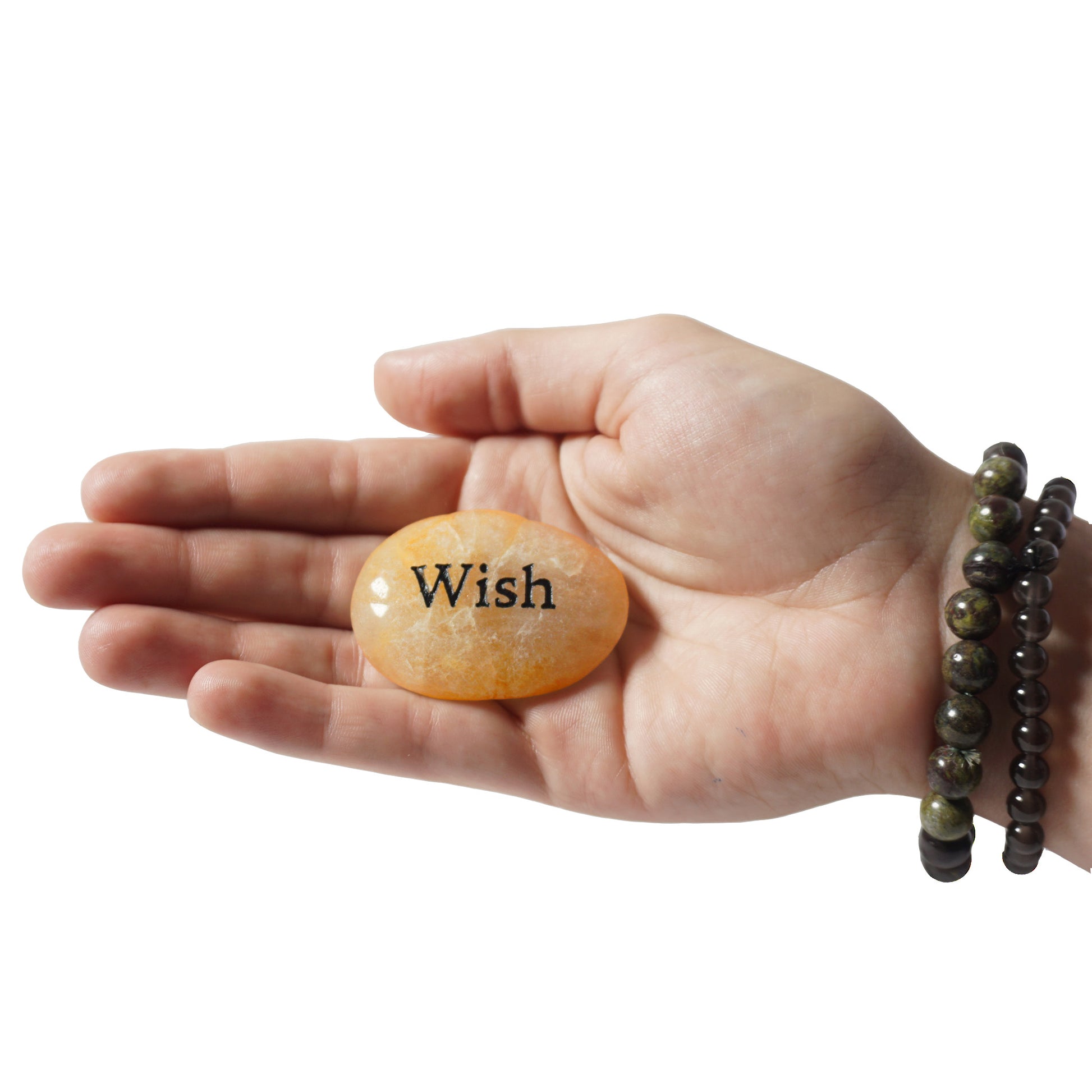 Hand holding a stone with 'Wish' engraved on it against a white background