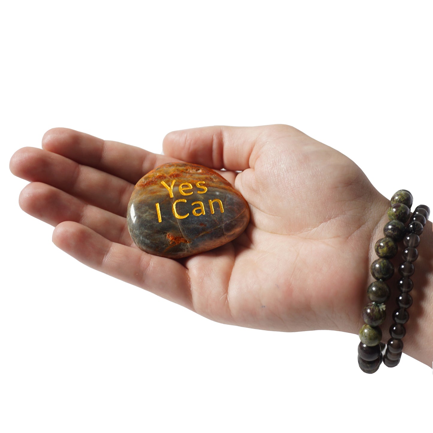 Hand holding a rock with 'Yes I Can' engraving on a white background
