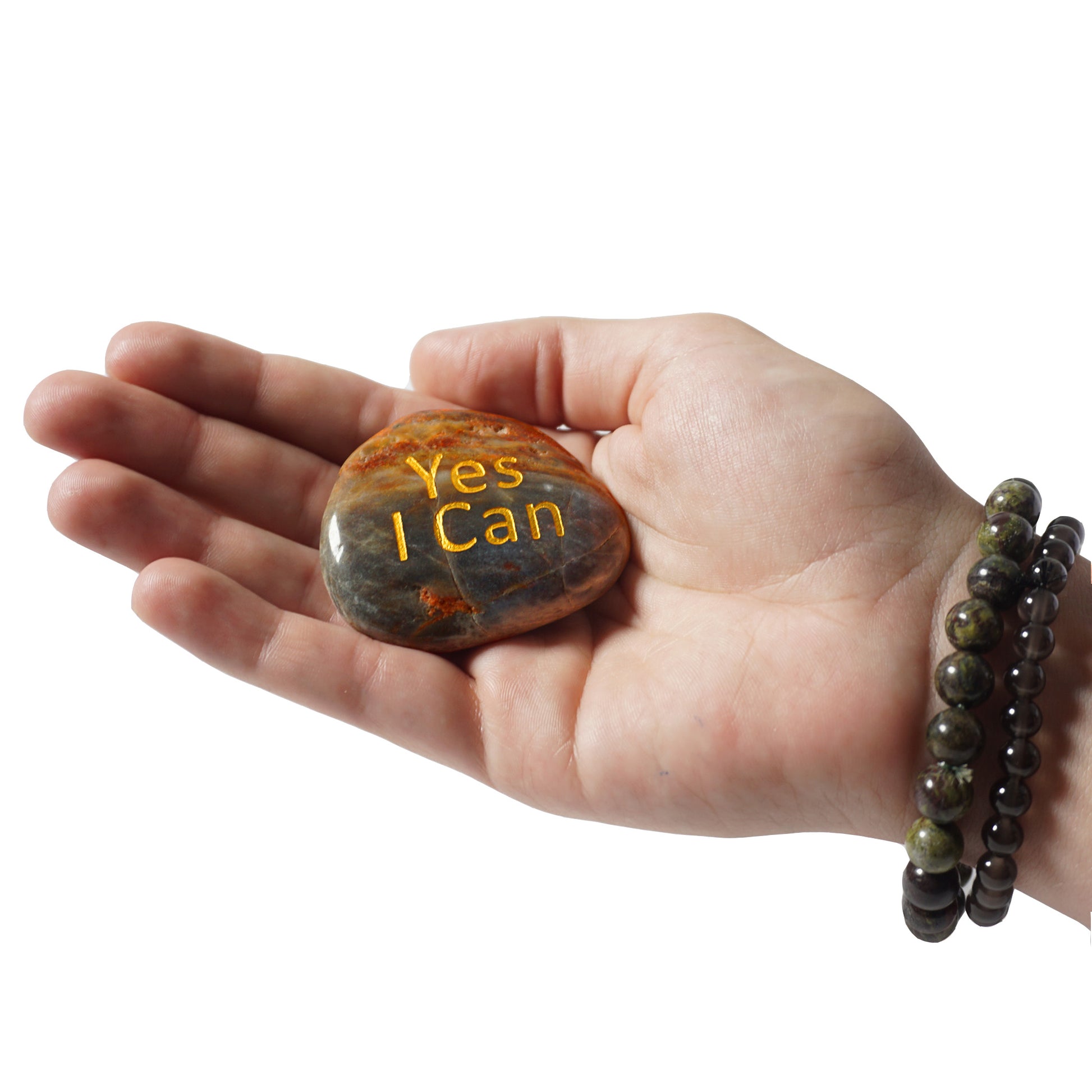 Hand holding a rock with 'Yes I Can' engraving on a white background
